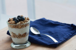 granola and yogurt in glass with blue napkin