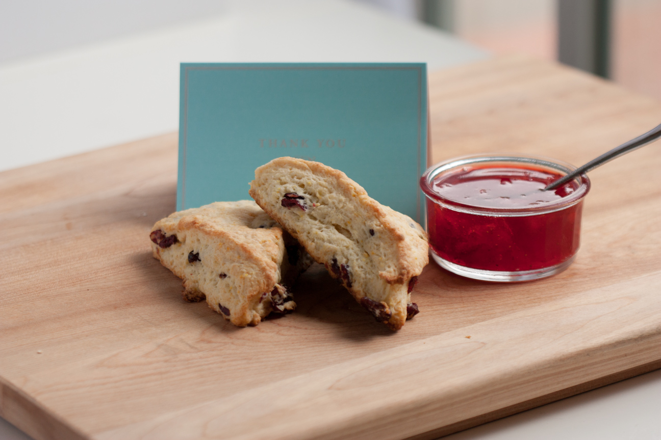 orange cranberry scones with jam on a cutting board with thank you card