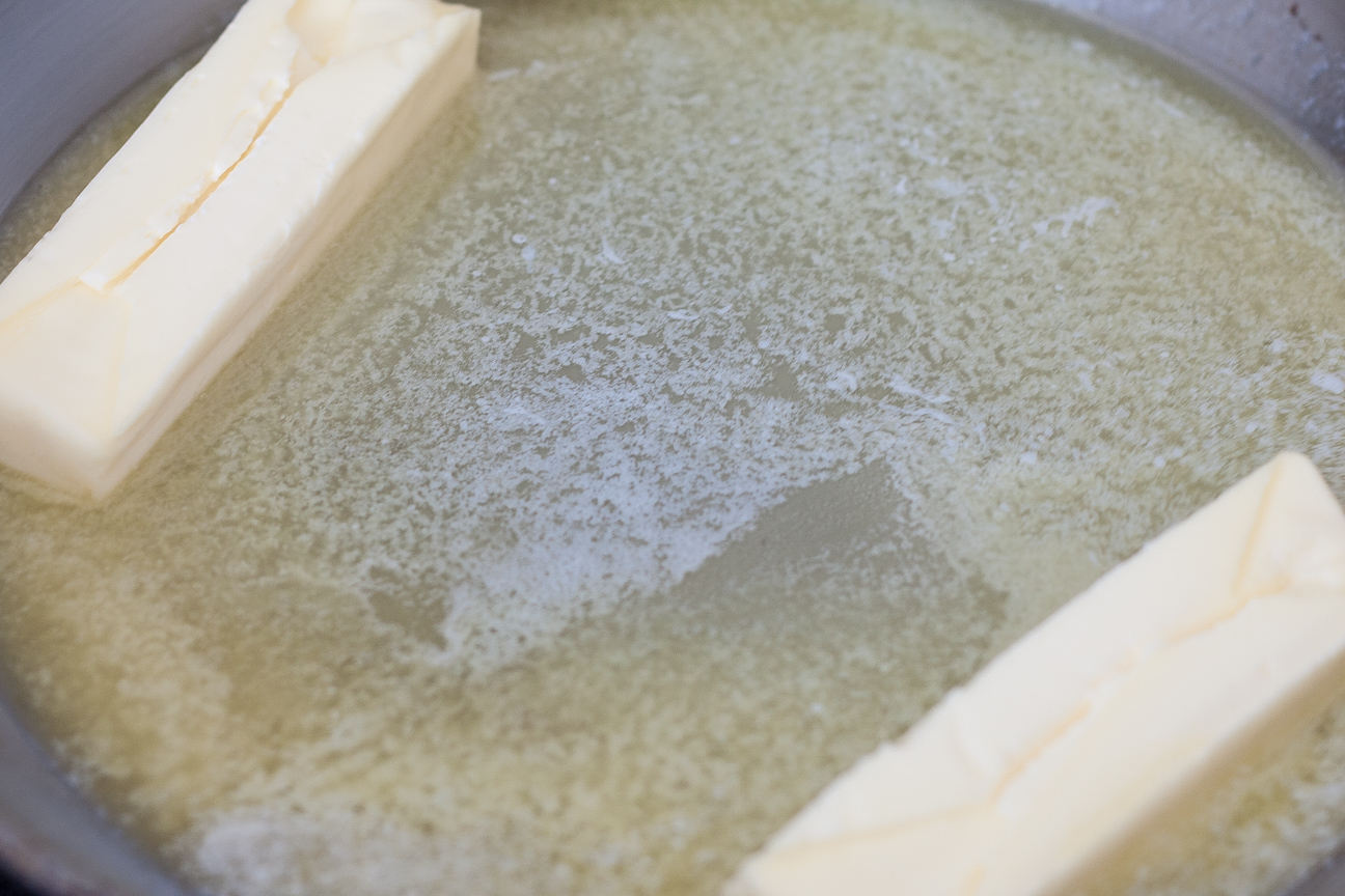 two sticks of butter melting in a pan