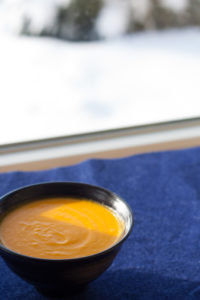 carrot lemon soup in bowl on blue napkin