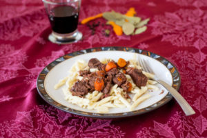 beef stew on plate with glass of red wine