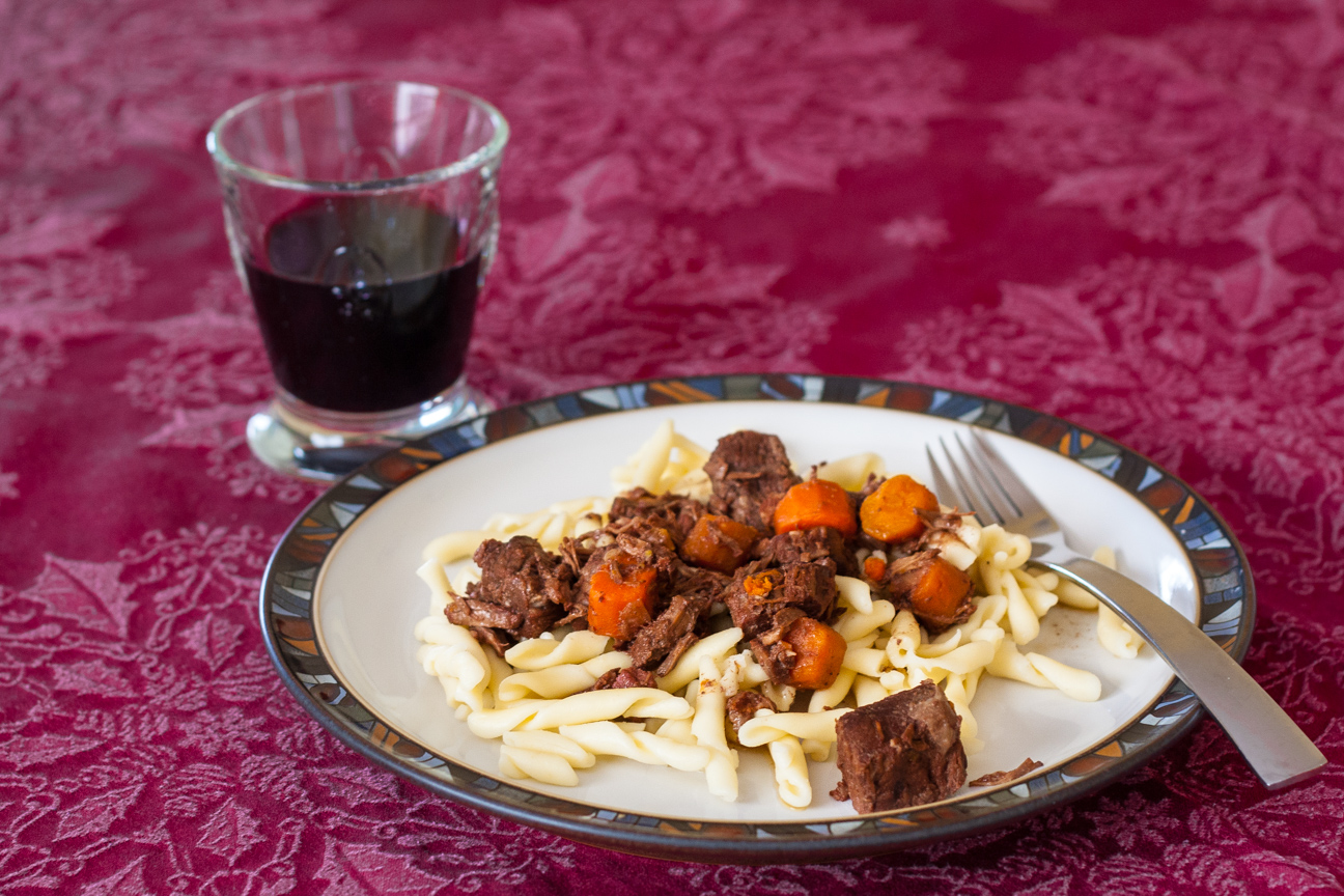 beef stew on plate with glass of red wine