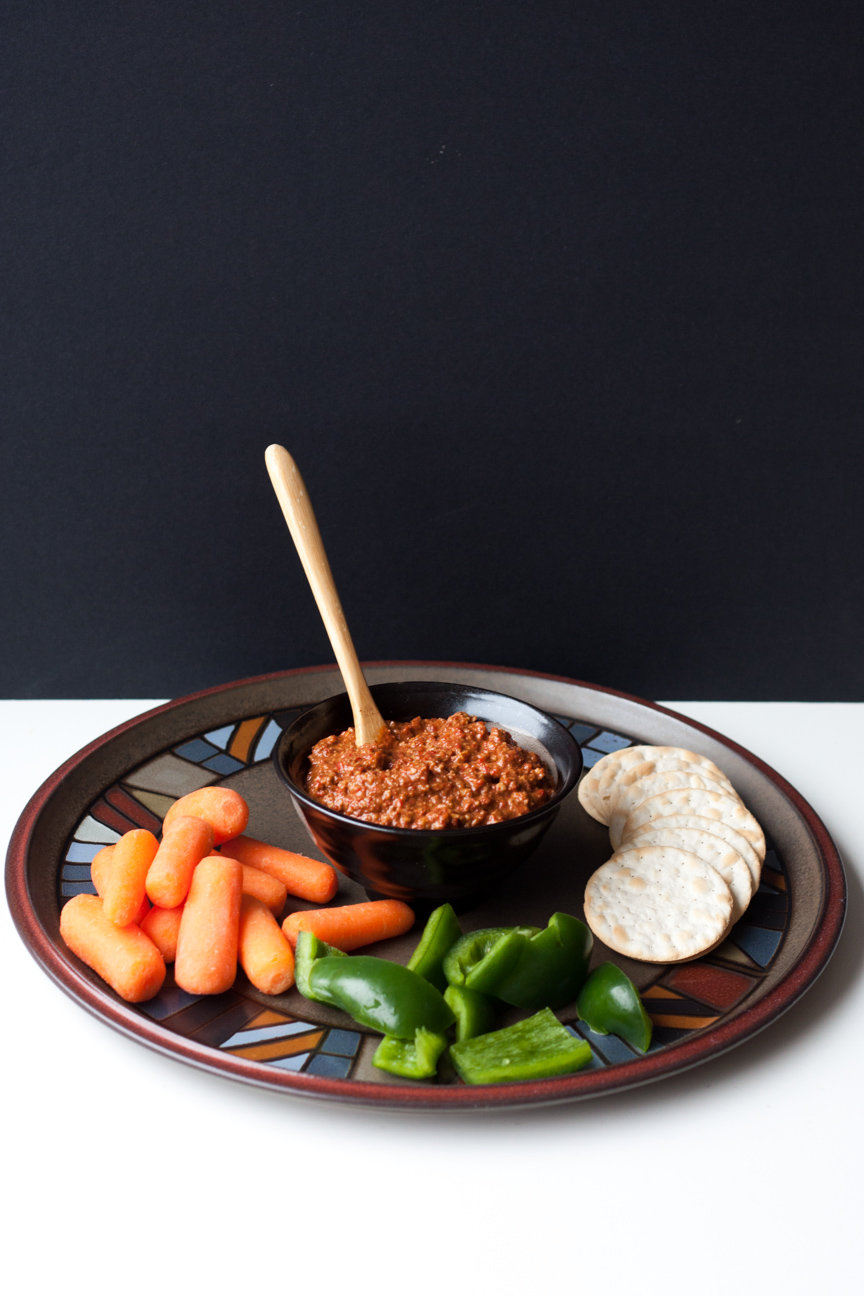 muhammara dip on a platter with vegetables and crackers