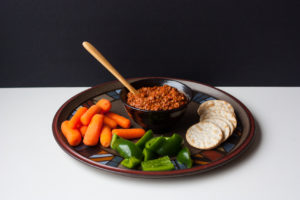 muhammara dip with vegetables and crackers on a platter