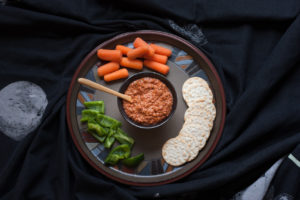 muhammara dip with raw vegetables on a plate