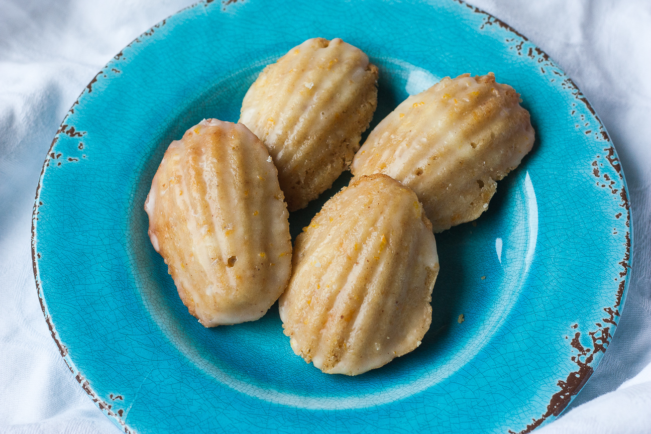 brown butter orange hazelnut madeleines on a teal ceramic plate