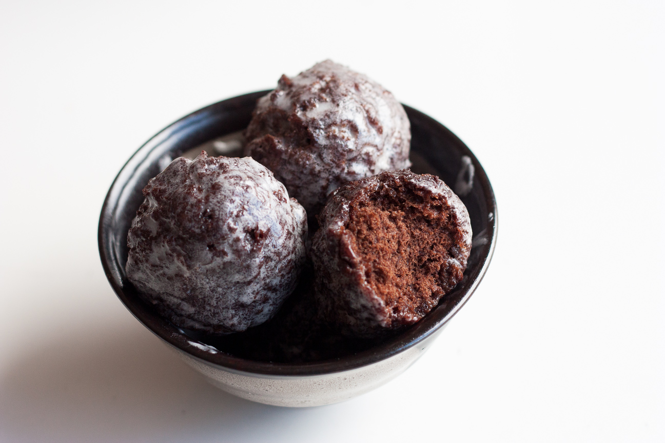 glazed chocolate donuts with a bite out of one