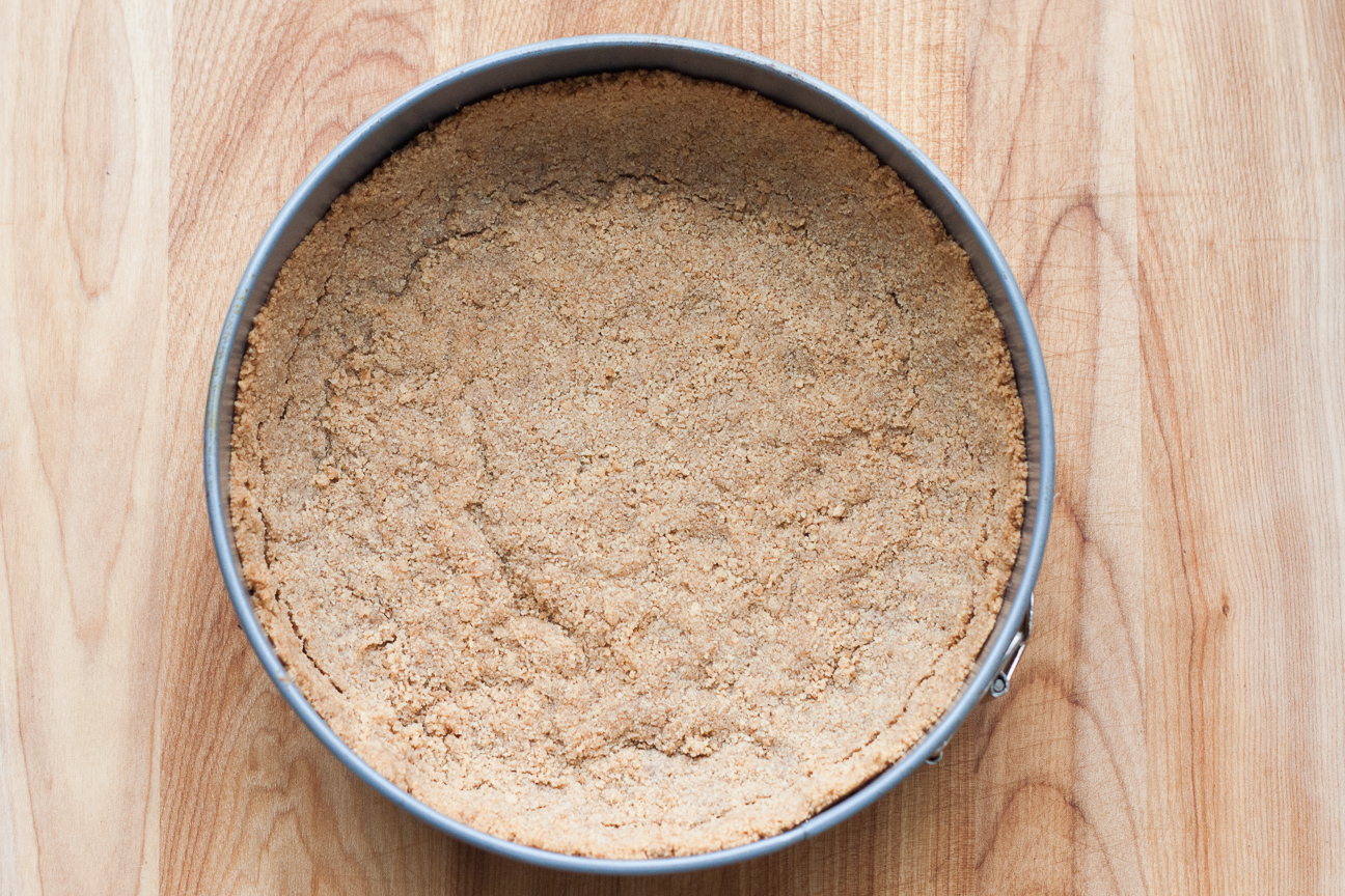 graham crust in a springform pan on a wood cutting board