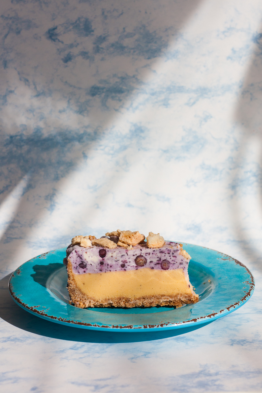 slice of blueberry mango ice cream cake on blue plate