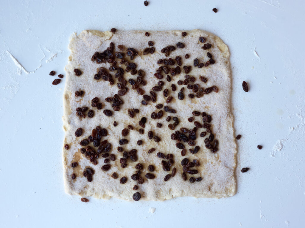 danish pastry dough rolled out and covered with raisins